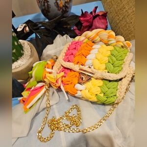 A lovely, vibrant colored, hand-knitted crossbody purse with a golden chain.